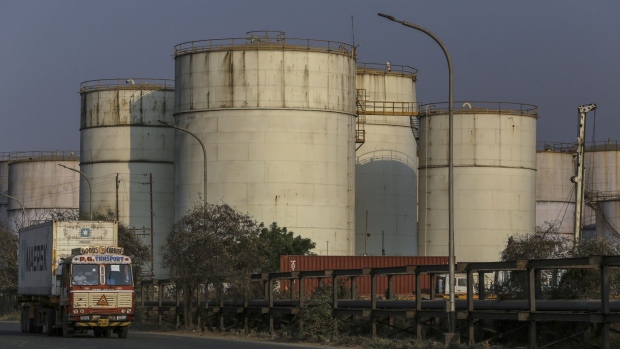 A container truck travels past oil storage tanks at Jawaharlal Nehru Port, operated by Jawaharlal Nehru Port Trust (JNPT), in Navi Mumbai, Maharashtra, India, on Monday, March 30, 2020. As billions of people stay home in the the world's major economic centers, consumption of everything from transport fuel to petrochemical feedstocks is in freefall. Refiners that have already been filling up their storage tanks with unsold products now have little choice but to partially shut down their plants. Photographer: Dhiraj Singh/Bloomberg