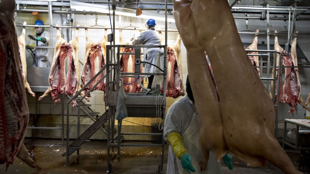 Pig carcasses hang from an overhead conveyor at a Smithfield Foods Inc. pork processing facility in Milan, Missouri, U.S., on Wednesday, April 12, 2017. WH Group Ltd. acquired Virginia-based Smithfield, the world's largest pork producer, in 2013 for $6.95 billion. As Smithfield can't export sausage, ham and bacon from its U.S. factories, because China prohibits imports of processed meat, WH Group opened an 800 million-yuan ($116 million) factory in Zhengzhou that will produce 30,000 metric tons of those meats when it reaches full capacity next year. Photographer: Daniel Acker/Bloomberg