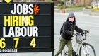 A woman checks out a jobs advertisement sign during the COVID-19 pandemic in Toronto