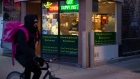 A food delivery courier cycles past a restaurant in Toronto's Chinatown, on Saturday March 21, 2020.