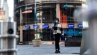 A pedestrian wearing a protective mask walks past the Nasdaq MarketSite in the Times Square neighborhood of New York. Photographer: Jeenah Moon/Bloomberg