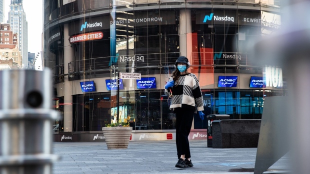 A pedestrian wearing a protective mask walks past the Nasdaq MarketSite in the Times Square neighborhood of New York. Photographer: Jeenah Moon/Bloomberg