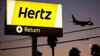 A plane flies as signage is displayed at dusk outside of a Hertz Global Holdings Inc. rental location at Los Angeles International Airport (LAX) in Los Angeles, California, U.S., on Tuesday, Nov. 7, 2017. Hertz is scheduled to release earnings on November 9. Photographer: Patrick T. Fallon/Bloomberg