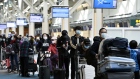 Travelers wearing protective masks wait in line in the international departures area in Vancouver International Aiport (YVR) in Vancouver, British Columbia, Canada, on Tuesday, March 17, 2020. Prime Minister Justin Trudeau's government is significantly restricting the entry of non-residents into Canada to combat the spread of the coronavirus. Photographer: Jennifer Gauthier/Bloomberg