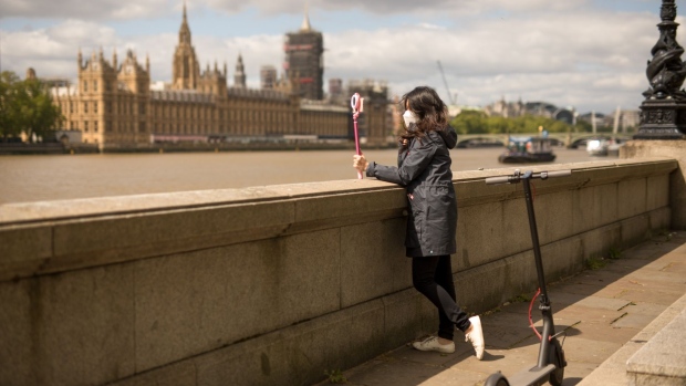 A pedestrian wearing a protective face mask takes a selfie in view of the Houses of Parliament in London on May 11. Photographer: Jason Alden/Bloomberg