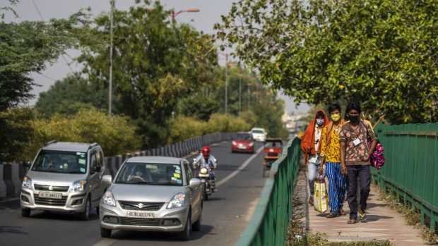 Migrant workers wearing protective masks walk along a sidewalk during a partial lockdown imposed due to the coronavirus in New Delhi, India, on Thursday, May 14, 2020. India spelled out the details of its massive rescue package that will initially help small businesses and utility companies as Prime Minister Narendra Modi gears to restart the economy cratered by the coronavirus pandemic. Photographer: Prashanth Vishwanathan/Bloomberg