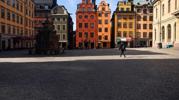 A pedestrian walks through an empty square in the Gamla Stan square in Stockholm on March 26. Photographer: Mikael Sjoberg/Bloomberg