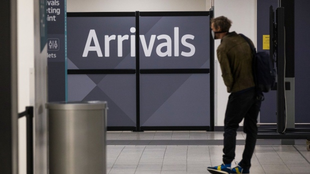 A traveler, wearing a protective face mask, passes through the arrivals area after landing at London Luton Airport in Luton, U.K., on Friday, May 1, 2020. Ryanair Holdings Plc will cut 3,000 jobs and said it will challenge some 30 billion euros ($33 billion) in state aid being doled out to save its European competitors. Photographer: Chris Ratcliffe/Bloomberg