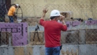 A worker holds on to a fence at a low-income housing construction site in Schenectady