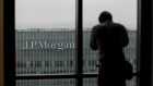 A man looks out of a window to the offices of JPMorgan Chase & Co. in the Canary Wharf business and shopping district in London. Photographer: Simon Dawson/Bloomberg