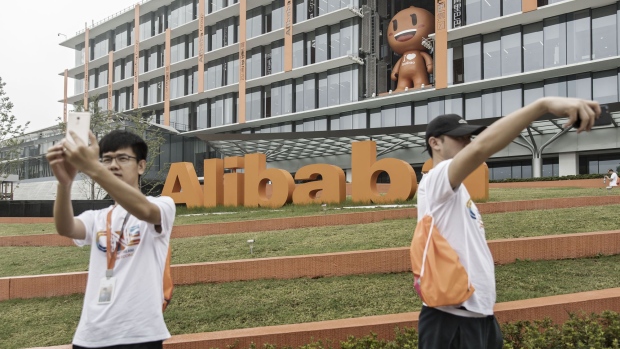Employees and visitors take selfie photographs in front of Alibaba Group Holding Ltd. signage at the company's headquarters in Hangzhou, China, on Friday, Sept. 8, 2017. After conquering grocery deliveries, Alibaba is setting its sights on a new part of China’s $4 trillion retail sector: department stores. Photographer: Qilai Shen/Bloomberg