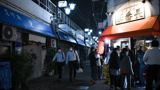 People wearing protective face masks walk past a restaurant at night in the Kamata district of Tokyo, Japan, on May 22, 2020. The Bank of Japan launched a new lending program worth 30 trillion yen ($279 billion) to support small businesses struggling amid the coronavirus but held off from adding major stimulus at an emergency meeting Friday. Photographer: Noriko Hayashi/Bloomberg