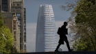 A person wearing a protective mask crosses Post Street in front of SalesForce Tower in San Francisco, California, U.S., on Wednesday, April 15, 2020. California Governor Gavin Newsom on Tuesday laid out rough benchmarks for reopening his state's economy - and radically reshaping daily life in the process - as he tried to bring other states into his West Coast coalition to fight the new coronavirus. Photographer: David Paul Morris/Bloomberg