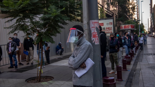 People wearing protective masks wait in line at the Unemployment Fund Administration office in Santiago, Chile. Photographer: Cristobal Olivares/Bloomberg