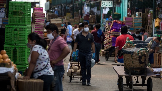 People wearing protective masks shop at a market in Lima, Peru. Photographer: Angela Ponce/Bloomberg