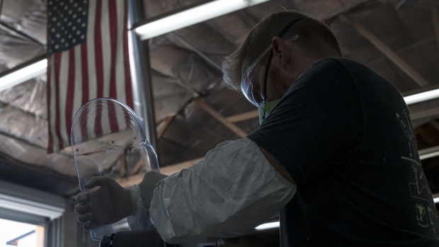 A worker wearing a protective mask, gloves, and glasses sands an edge of a face shield at Mask & Shield, a division of Monster City Studios, in Fresno, California, U.S., on Wednesday, May 27, 2020. Monster City Studios, a company that normally makes amusement park and movie props, has pivoted to manufacturing MCS face shields with forehead protection. Photographer: David Paul Morris/Bloomberg