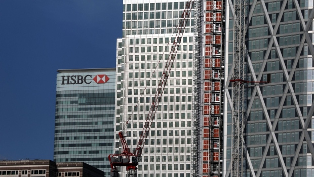 A construction crane stands near the offices of HSBC Holdings Plc, left, next to One Canada Square skyscraper, center, in the Canary Wharf business, financial and shopping district in London, U.K