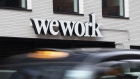 A taxi drives past a logo for WeWork the co-working office space, operated by the parent company We Co., on City Road in London, U.K., on Monday, Oct. 7, 2019. While WeWork has been rapidly expanding in Canada, the New York-based company is facing challenges on multiple fronts with Landlords in London and New York amongst the most exposed to any further deterioration at the co-working firm. Photographer: Bryn Colton/Bloomberg