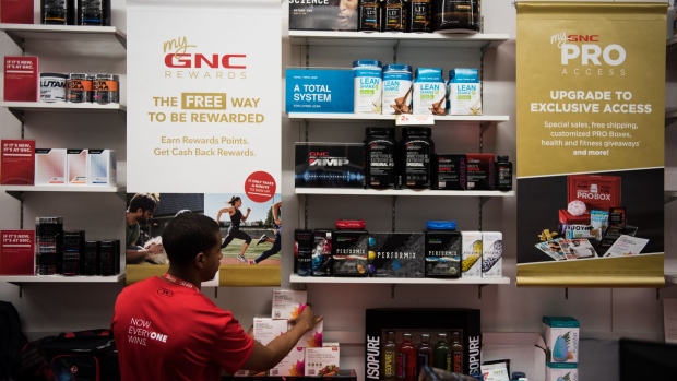 An employee restocks products on a table at GNC Holdings store. Photographer: Mark Kauzlarich/Bloomberg