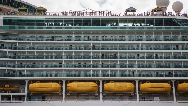 Passengers stand on board the Royal Caribbean Cruises Ltd. Navigator Of The Seas cruise ship at the Port of Miami in Miami, Florida, U.S., on Monday, March 9, 2020. At the world's busiest cruise port, thousands of vacationers paid little heed to a government warning that Americans should avoid setting sail on the massive ships. Photographer: Jayme Gershen/Bloomberg