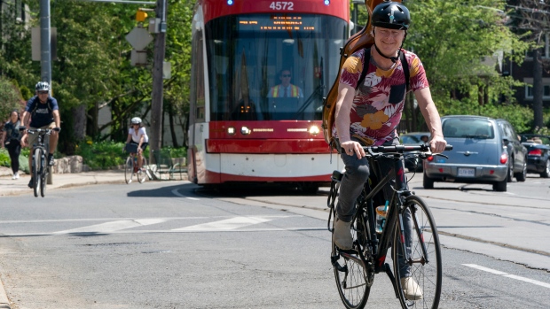 Cyclists ride up a hill with a TTC streetcar in Toronto
