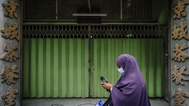 A pedestrian wearing a protective mask walks past a closed store during a partial lockdown imposed due to the coronavirus in Kuala Lumpur, Malaysia, on Wednesday, May 20, 2020. The Malaysian government is working to implement its 260 billion ringgit ($60 billion) stimulus package, the biggest in Southeast Asia as proportion of gross domestic product, while promising another set of measures to bolster an economy struggling with the effects of the pandemic. Photographer: Ian Teh/Bloomberg