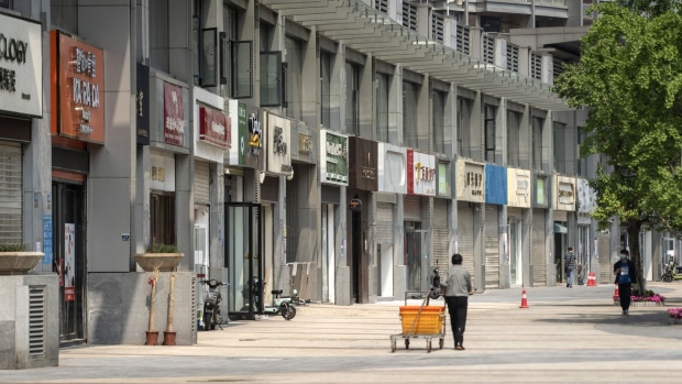 A pedestrian pulls a cart past closed stores on a near-empty street in Wuhan, China, on Friday, May 1, 2020. The lifting on April 8 of the unprecedented lockdown on Wuhan -- where the virus pathogen first emerged -- was a milestone. Stringent nationwide restrictions in China meant the world's second-largest economy recorded its deepest contraction in decades over the first quarter. Photographer: Qilai Shen/Bloomberg