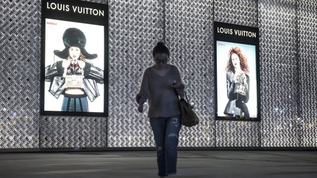 A pedestrian walks past a LVMH Moet Hennessy Louis Vuitton SE fashion boutique at night in Shanghai, China, on Tuesday, Oct. 25, 2016. The world's luxury-goods market stopped growing this year, according to a forecast from researcher Bain & Co., as the industry struggles to emerge from one of its weakest periods since the global recession. Photographer: Qilai Shen/Bloomberg