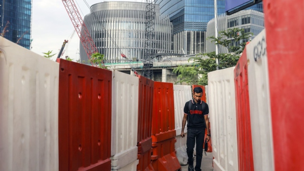 A pedestrian walks between barricades at the under construction Tun Razak Exchange (TRX) financial district in Kuala Lumpur, Malaysia, Wednesday, Oct. 23, 2019. Southeast Asia's tallest skyscraper was once shadowed by the 1MDB scandal that has upended the nation's politics and implicated global banks in criminal cases. It now seeks to shed that past by plying prospective tenants with marble walls and mirrored ceilings. Photographer: Joshua Paul/Bloomberg