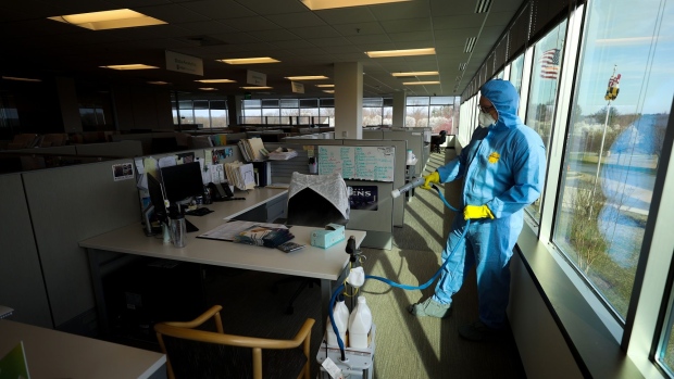 A worker sprays disinfectant at an office building in Bayshore, New York, on April 21. Photographer: Kevin Mazur/Getty Images