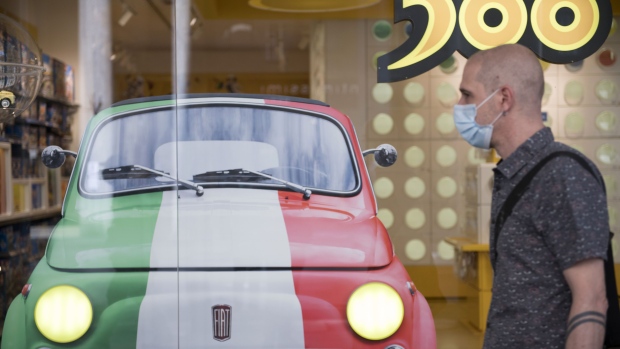 A pedestrian wearing a protective mask walks past a shop window with a sticker of a Fiat 500 in Turin. Photographer: Stefano Guidi/Getty Images Europe