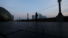 A lone pedestrian walks along the Thames Path in view of skyscrapers in the City of London square mile financial district on April 9. Photographer: Simon Dawson/Bloomberg