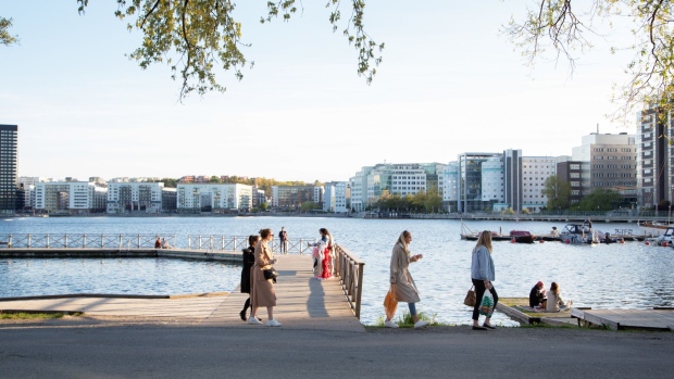 A group of people socialize on a jetty on the water's edge at Tantolunden in Stockholm, Sweden, on Friday, May 22, 2020