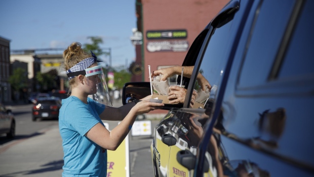 A server brings an order to a parked car outside a diner in Picton, Ontario, Canada, on Saturday, June 13, 2020. Ontario businesses ranging from hair salons, shopping malls, swimming pools, beaches and campgrounds were allowed to reopen Friday and restaurants and bars opened their outdoor dining areas and patios for the first time since the pandemic began. Photographer: Cole Burston/Bloomberg