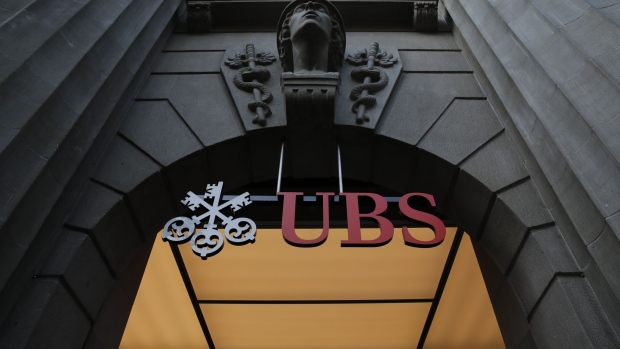 A sign hangs above the entrance to the UBS Group AG headquarters in Zurich, Switzerland, on Monday, Oct. 14, 2019. The spying scandal roiling Credit Suisse Group AG has also created a big headache at UBS a stone's throw away in Zurich: What to do about its star hire Iqbal Khan. Photographer: Stefan Wermuth/Bloomberg