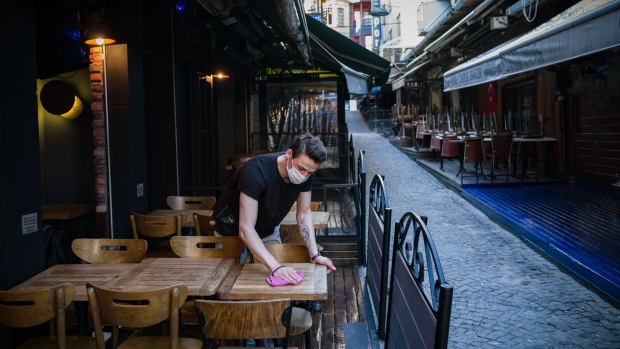 An employee cleans the terrace tables of the Elma Pub cafe ahead of opening following the easing of lockdown in Istanbul, Turkey, on Monday, June 1, 2020. Turkey unveiled its most expansive program of credit incentives in four years to help the economy recover from the coronavirus pandemic.