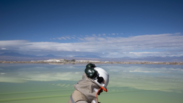 A visitor walks past a brine lake at a lithium mine on the Atacama salt flat in the Atacama Desert, Chile.
