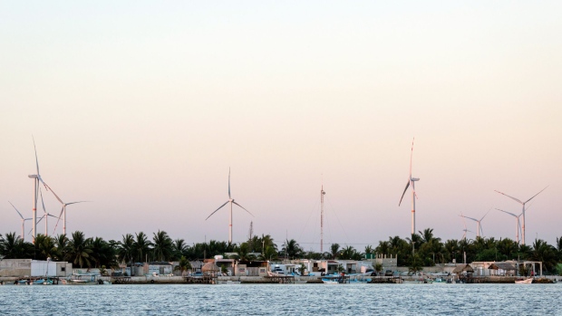 A wind farm stands in the town of Dzilam de Bravo near Merida, Yucatan, Mexico, on Sunday, May 20, 2018. At the end of the last century, before the commodities boom brought a wave of development to Latin America, opposition to the blight of new electricity infrastructure was rare. People just wanted the energy. Now that 100 percent of the region's biggest economies have access to power, the "Not in my backyard" movement—or Nimby'ism—that has long been the norm from Europe to the U.S. is creeping in here, too. Photographer: Brett Gundlock/Bloomberg
