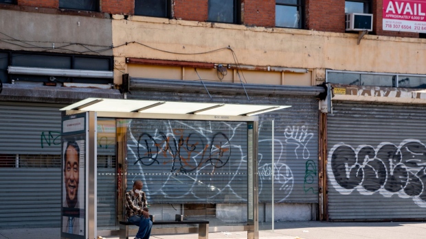 A person sits at a bus stop next to closed businesses in Brooklyn, New York on June 17. Photographer: David Dee Delgado/Bloomberg