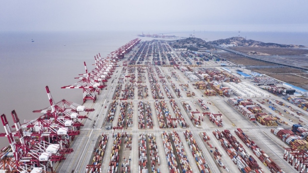 Shipping containers sit stacked next to gantry cranes at the Yangshan Deep Water Port in this aerial photograph taken in Shanghai, China, on Tuesday, Feb. 4, 2020. Chinese officials are hoping the U.S. will agree to some flexibility on pledges in their phase-one trade deal, people familiar with the situation said, as Beijing tries to contain a health crisis that threatens to slow domestic growth with repercussions around the world.