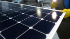 An employee of SunPower Corp. trims the edges and checks solar panels at the SunPower Corp. module manufacturing plant at Flextronics in Milpitas, California, U.S., on Wednesday, Aug. 24, 2011. Photographer: David Paul Morris/Bloomberg