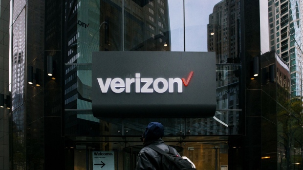 A pedestrian passes in front of a Verizon Communications Inc. store in Chicago. Photographer: Taylor Glascock/Bloomberg