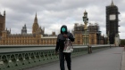 A commuter wearing a protective face mask crosses Westminster Bridge in view of the Houses of Parliament and Elizabeth Tower, also known as Big Ben, in London, U.K., on Monday, May 11, 2020. U.K. Prime Minister Boris Johnson will flesh out his plan for lifting the U.K. lockdown in Parliament as he seeks to get more people back to work, even as resistance from politicians and labor unions laid bare the hurdles facing the government as it tries to kickstart the economy. Photographer: Jason Alden/Bloomberg