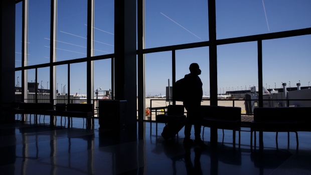 A traveler wearing a protective mask walks through an airport. Photographer: Patrick T. Fallon/Bloomberg
