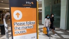 Shoppers pass a sign indicating the direction of walking around the Lakeside shopping centre, operated by Intu Properties Plc, in Thurrock, U.K., on Friday, June 19, 2020. U.K. retail sales started to recover last month from their precipitous drop during the coronavirus lockdown.