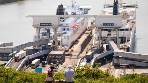 A couple sit on a bench of in view of ferries loading and unloading trucks at the Port of Dover Ltd. in Dover, U.K., on Wednesday, May 27, 2020. The U.K. announced its post-Brexit tariffs regime, cutting import duties on many products while protecting industries such as automotive and agriculture, as the country turns its focus toward global trade beyond Europe.