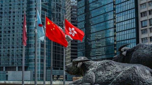 The flag of the Hong Kong Special Administrative Region, right, flies alongside the flag of China outside the Exchange Square complex, which houses the Hong Kong Stock Exchange, in Hong Kong, China, on Friday, May 29, 2020. The struggle to maintain confidence in Hong Kong's future is manifesting in its stock and currency markets.