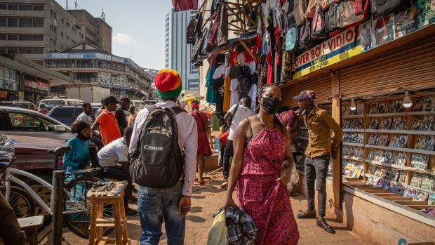 A pedestrian wearing a protective mask walks past market vendors in downtown Kampala, Uganda, on June 23, 2020. Photographer: Esther Ruth Mbabazi/Bloomberg
