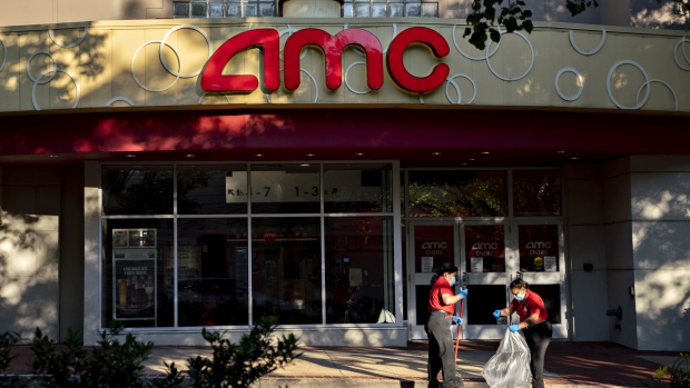 Workers wearing protective masks clean in front of an AMC movie theater in Arlington, Virginia. Photographer: Andrew Harrer/Bloomberg