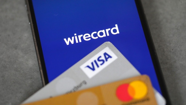 Credit cards next to a mobile device displaying the Wirecard app launch screen. Photographer: Alex Kraus/Bloomberg